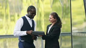 Multicultural business partners smiling and using a tablet in Melbourne's downtown, showcasing collaboration and connectivity in a modern urban setting - Powered by Shutterstock - Get 15% off with code: PIKWIZARD15