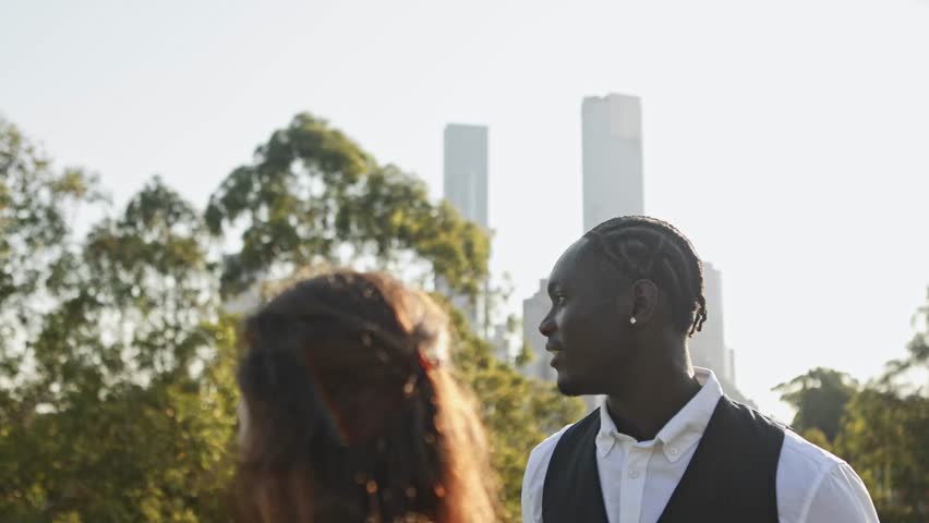 Professional businesspeople from diverse backgrounds engaging in collaborative discussion within downtown Melbourne park, with modern skyscrapers framing urban landscape backdrop