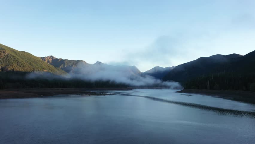 4K aerial drone footage of sunrise at Wynoochee Lake dam in Olympic National Forest, Washington State, USA, showing calm water, low clouds, and forested mountain landscape in peaceful morning 