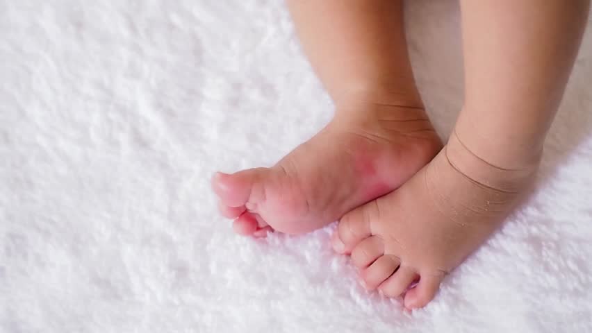 Close up of newborn baby feet on white blanket