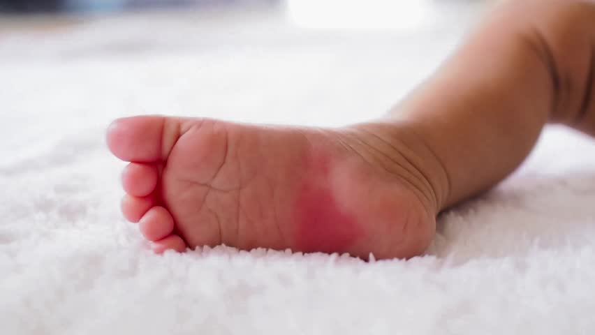 Close up of newborn baby feet on white blanket
