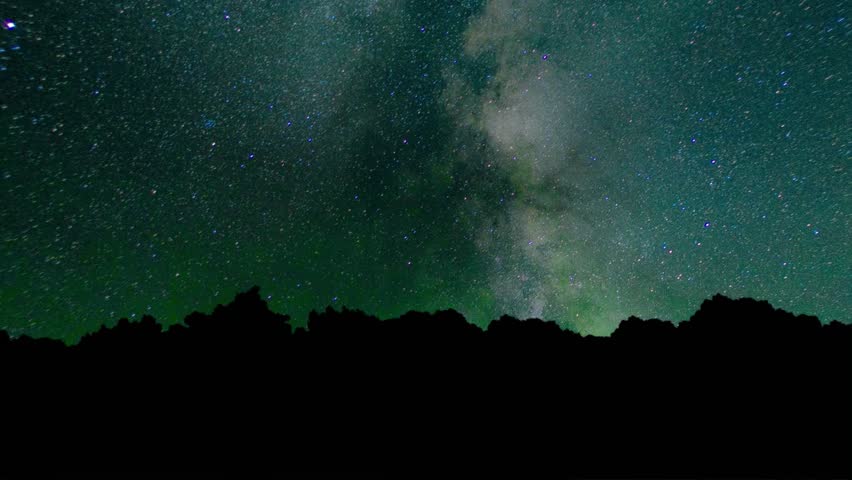 view Milky Way galaxy stretching across star filled night sky above dark rocky mountain silhouettes. astrophotography beauty of universe, cosmic dust, millions of stars in deep space. starry nebula