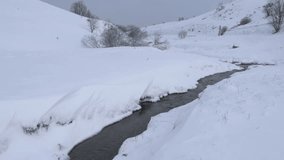 Winter creek flowing through snowy hills landscape. Small mountain river flowing through a tranquil, snow-covered valley during winter - Powered by Shutterstock - Get 15% off with code: PIKWIZARD15