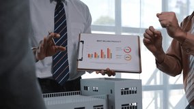 Professional architect presenting best selling product statistics on clipboard while standing near building scale model, sharing insights with colleagues in bright, modern office workspace - Powered by Shutterstock - Get 15% off with code: PIKWIZARD15
