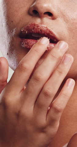 Skincare, woman and apply scrub to lips in studio, exfoliate treatment and soft texture for wellness. Self care, dermatology and person with product for smooth aesthetic, cosmetics and sugar mask.