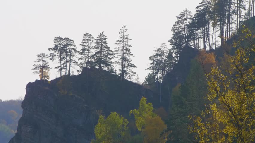 Scenic footage captures the majestic Rock Kalim Uscan in the South Ural Mountains of Russia, showcasing a beautiful autumn landscape with vibrant foliage and rugged rock formations under a clear sky.