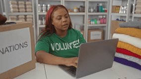 Woman wearing volunteer shirt types on laptop next to donation boxes at center; community generosity dedication service. - Powered by Shutterstock - Get 15% off with code: PIKWIZARD15