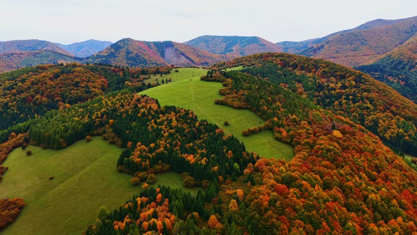 Drone footage showcasing vibrant autumn colors over the rolling hills and forested mountains of Sulov in Slovakia. A stunning natural landscape perfect for seasonal and travel visuals.