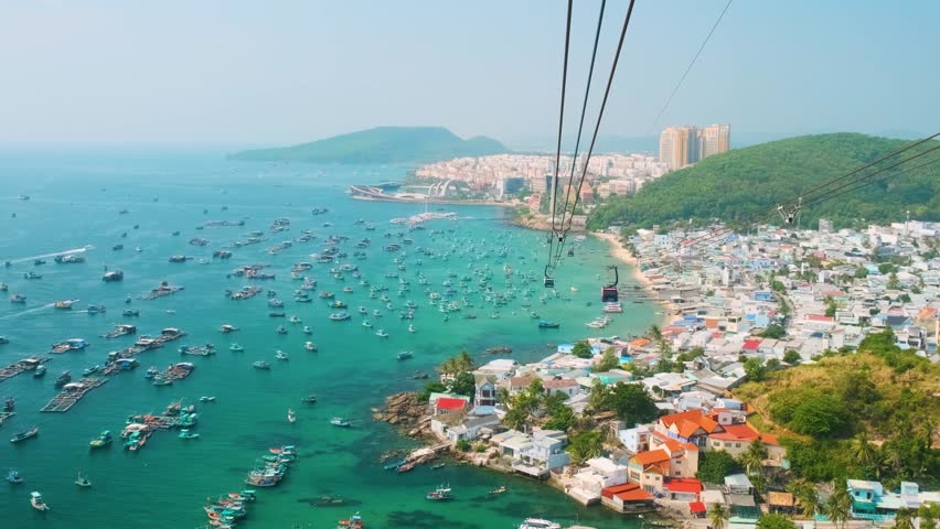 Aerial view of An Thoi harbor with coastal fishermen village, fishing boats, turquoise sea and modern cable car ride on Phu Quoc island, Vietnam. Modern Hon Thom cable car cabin