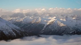 Dramatic snowy mountain peaks rising above sea of clouds in time lapse style, showcasing majestic alpine landscape with misty valleys and golden light on snow-covered summits. - Powered by Shutterstock - Get 15% off with code: PIKWIZARD15