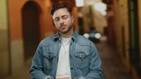 Young man with a beard wearing a denim jacket contemplating in a city street setting outdoors, highlighting urban lifestyle and casual fashion in an evening light ambiance. - Powered by Shutterstock - Get 15% off with code: PIKWIZARD15