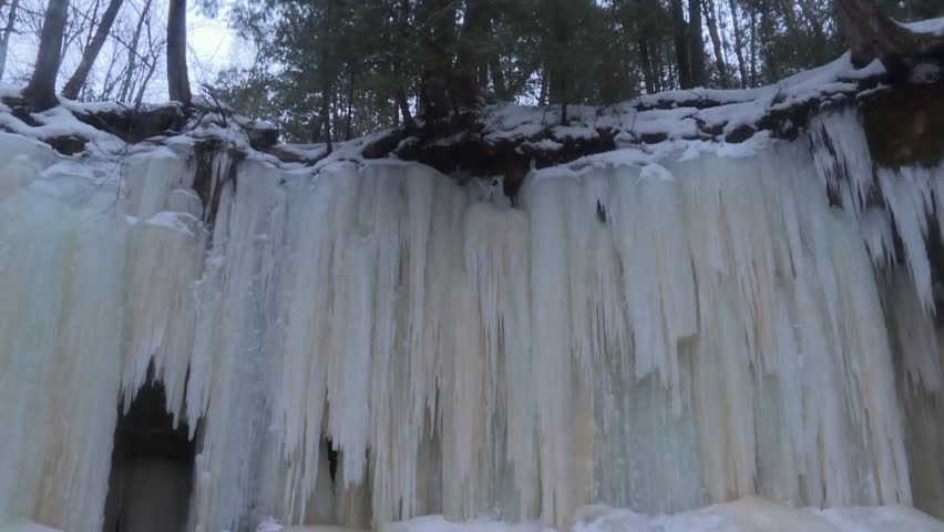 Melting Snow Over A Cliff At Rock River Canyon Ice Caves Near Eben Junction In Upper Peninsula, Michigan. Tilt-down Shot