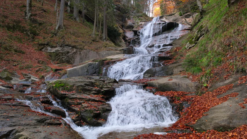 Scenic waterfall cascading over rocks in a mountain forest during the beautiful autumn season