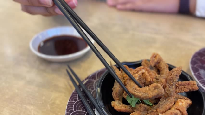 Close up video of chopsticks dip crispy fried salmon skin into soy sauce in a Japanese restaurant. Soft bokeh, natural table light, clean copy space—loopable b-roll for menus, promos, and reels
