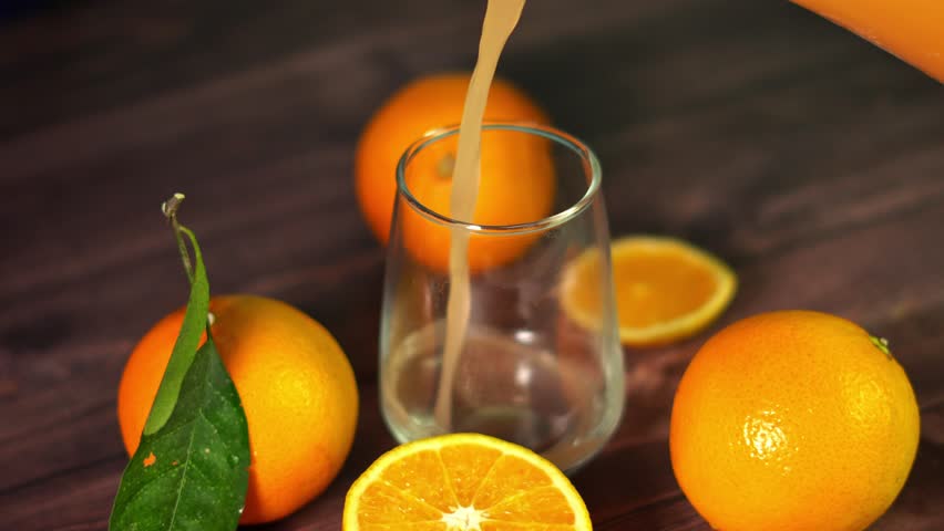 orange juice and oranges on a wooden table.