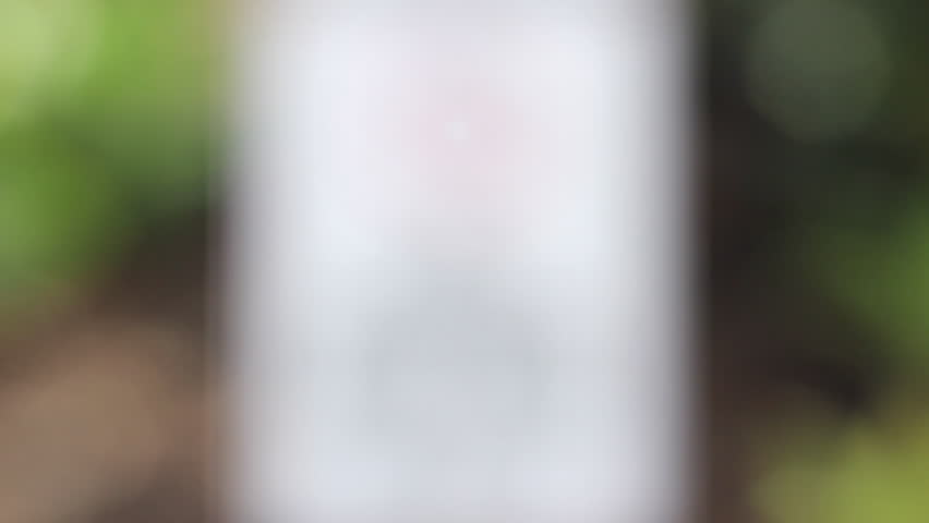 Blurred sign stating 'no skateboards, bicycles or rollerblades' in a garden setting with plants