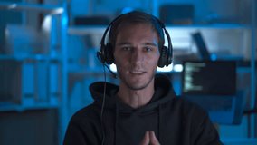 Caucasian male IT support specialist working in dark office in front of computer screen at night, wearing headset, talking with customer, and providing technical assistance. Concept of remote support. - Powered by Shutterstock - Get 15% off with code: PIKWIZARD15