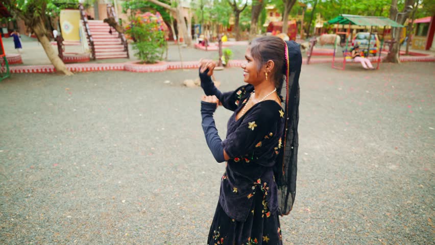 Woman performs folk steps at village fair by heritage fest, Draped dancer spins elegantly close to community celebration, Rural carnival features female in bright costume, Cultural gathering near park