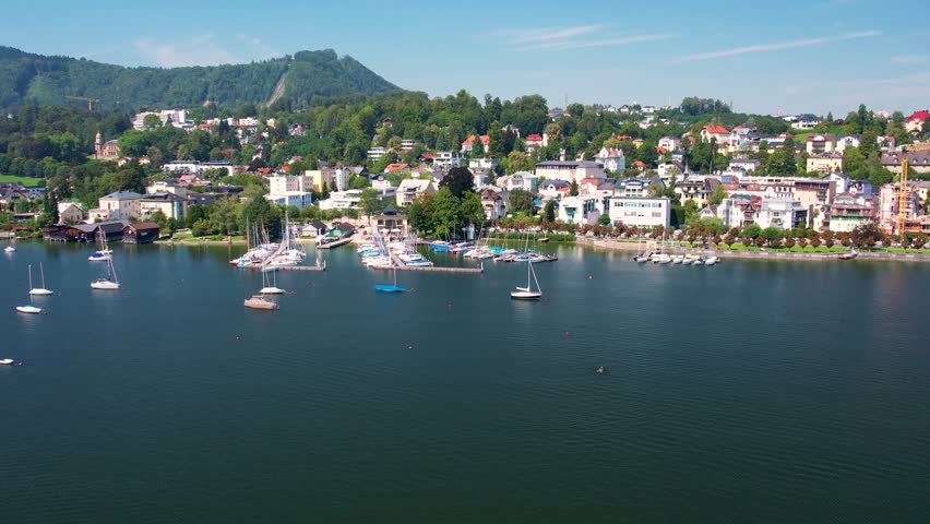 Aerial of beautiful resort town Gmunden on mountain Lake Traunsee, Salzkammergut. Serene lake, high Alp mountain, boats and picturesque buildings along the shoreline. Austria tourism and scenic places