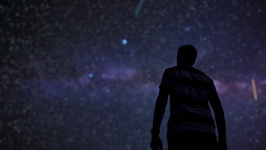 Silhouette of a man and countryside under the Milky Way stars.