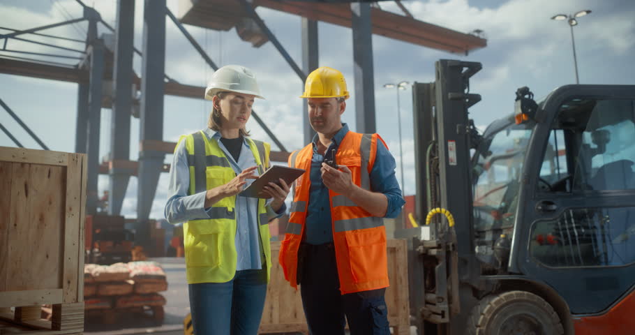 Dock Worker and Tally Clerk Manage Port Logistics Using a Tablet and Walkie-talkie, Surrounded by Shipping Containers and Forklifts. Commercial Cargo Shipment Operation