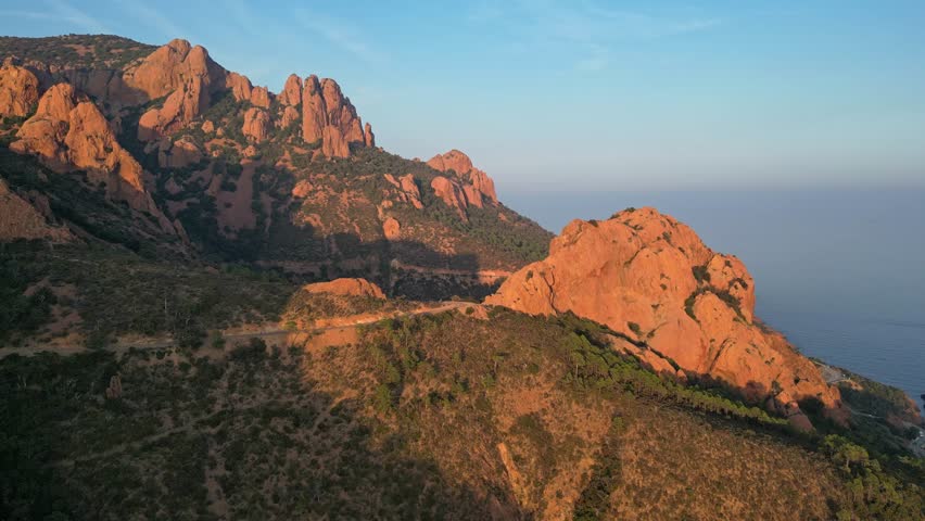 Panoramic aerial view of Esterel Mountains red cliffs overlooking the Mediterranean Sea on the French Riviera, Southern France, at sunset – dramatic mountain landscape and scenic coastline