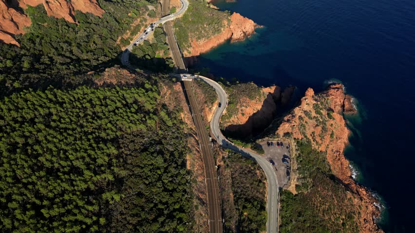 Aerial panoramic view of a winding mountain road along steep cliffs above the turquoise Mediterranean Sea, Esterel Mountains, French Riviera, Southern France – cinematic travel, scenic nature, adventu