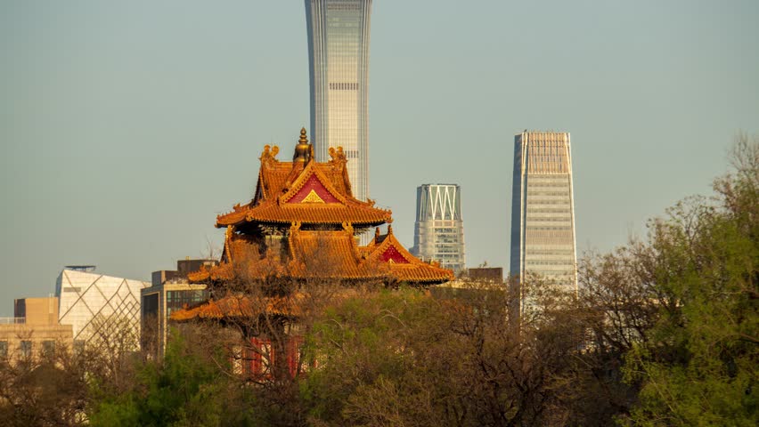 Traditional Chinese pagoda with ornate golden roofs contrasting against modern Beijing skyscrapers and CBD towers in warm evening light