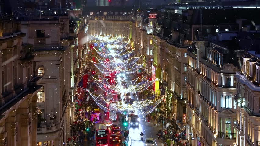 Christmas in London concept with decorated, festive shopping streets in the city center and snow falling during night time