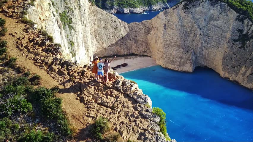 Beautiful panoramic view of three people against the backdrop of rocks and the sea.