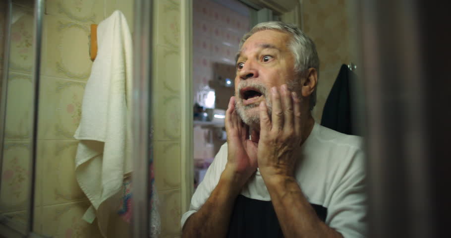 Older man cupping face in shock, mouth open, eyes wide with disbelief and fear, a powerful moment of emotional intensity and personal realization
