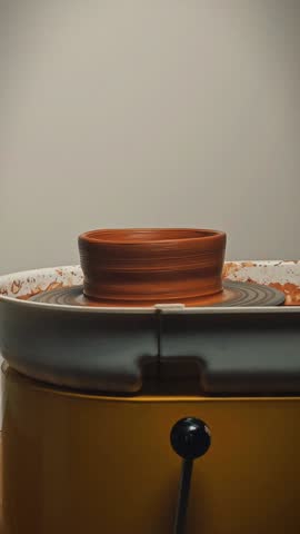 Pottery wheel in motion: close-up spinning wet clay. Manufacturing of ceramics, dishware, and handicraft in a workshop