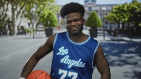 Man holding basketball with bare forearm exposed, wearing blue los angeles jersey number 77 on street plaza; confidence athletic spirit. - Powered by Shutterstock - Get 15% off with code: PIKWIZARD15