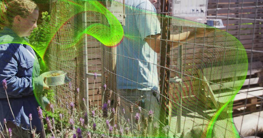 Pet care couple feeding cat with metal bowls through wire-mesh fence unlatching gate allowing exit. Gardening, companionship, tranquility, rustic, outdoor, harmony, leisure