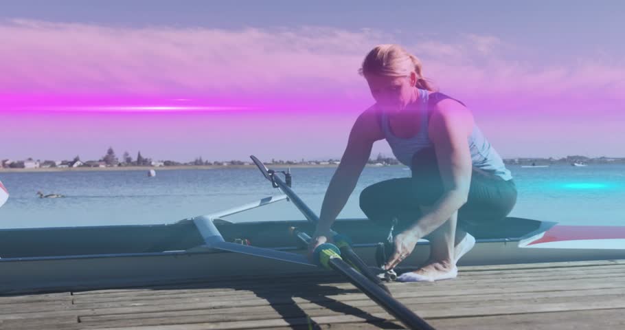 Stepping onto wooden dock, mature rowing athlete kneeling and adjusting oar rigging for boat launch. Outdoor, watercraft, sport, fitness, aquatic, determination, leisure