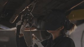 Female welder activating torch under car, sparking seam while clear auto code updating weld data. Industrial, craftsmanship, innovation, technology, mechanics, precision, maintenance - Powered by Shutterstock - Get 15% off with code: PIKWIZARD15