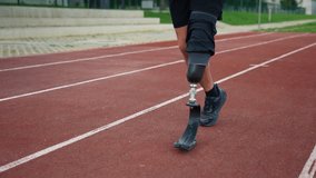 Athlete with a limb loss running on track using assistive prosthetic gear, blade featuring a heel plate, to achieve speed and agility, close up. - Powered by Shutterstock - Get 15% off with code: PIKWIZARD15