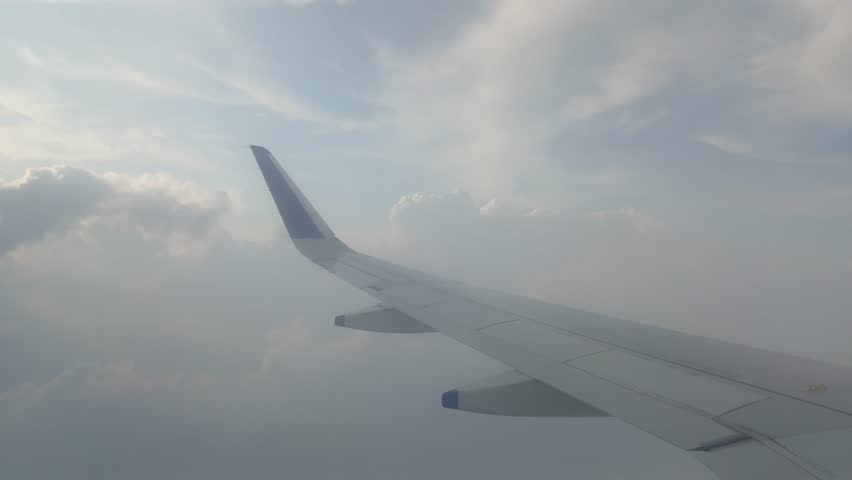 view from airplane window with cloudy sky, wing of airplane, view from the plane.	

