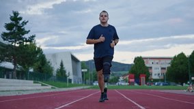 Man with disability wearing a prosthetic leg with a blade running on an outdoor athletic track, slow motion front view. Sport, motivation, and diversity concept. - Powered by Shutterstock - Get 15% off with code: PIKWIZARD15