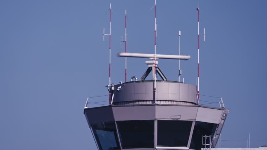 Looking up to airport control tower with turning radar and antenna at Swiss Zurich Airport on a sunny autumn day. Movie shot October 18th, 2025, Zurich, Switzerland.