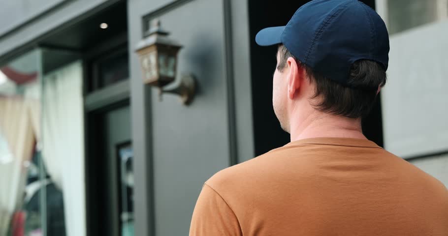 Casual man in baseball cap walking by urban store, exploring city lifestyle. Street fashion, summer day, downtown.