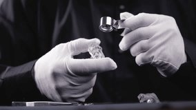 Jeweler examining with magnifying glass natural rough diamond to evaluate flaws and inclusions, evaluates gemstone for cutting on factory. - Powered by Shutterstock - Get 15% off with code: PIKWIZARD15