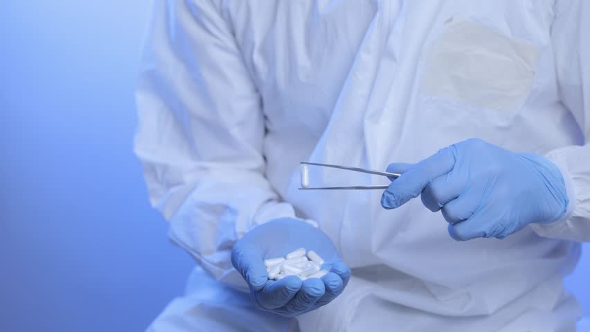 Medical production, worker inspects pill capsules with medicine quality in pharmaceutical facility.