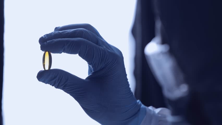 Medical production, worker inspects pill capsules quality in pharmaceutical facility.