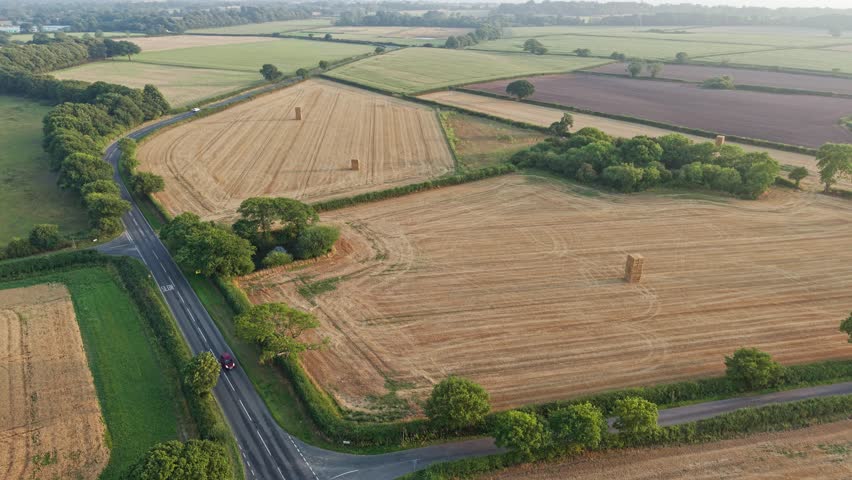 An aerial view shows piles of hay bales in a wheat field after harvest on the Wirral, England.
