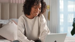 African American girl using laptop in bed at home office typing chatting reading writing email. Young black woman having virtual meeting online chat video call conference. Work learning from home - Powered by Shutterstock - Get 15% off with code: PIKWIZARD15