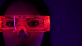 Caucasian woman wearing cyber glasses with red lights looking at the camera. With glitch noise on the video. Dark background. Close-up - Powered by Shutterstock - Get 15% off with code: PIKWIZARD15