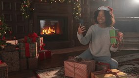 Merry Christmas. African woman in Santa hat having video chat in smartphone. Blogger in festive mood recording video in social network. Girl having video call with friends family celebrating Christmas - Powered by Shutterstock - Get 15% off with code: PIKWIZARD15