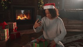Merry Christmas. African woman in Santa hat having video chat in smartphone. Blogger in festive mood recording video in social network. Girl having video call with friends family celebrating Christmas - Powered by Shutterstock - Get 15% off with code: PIKWIZARD15