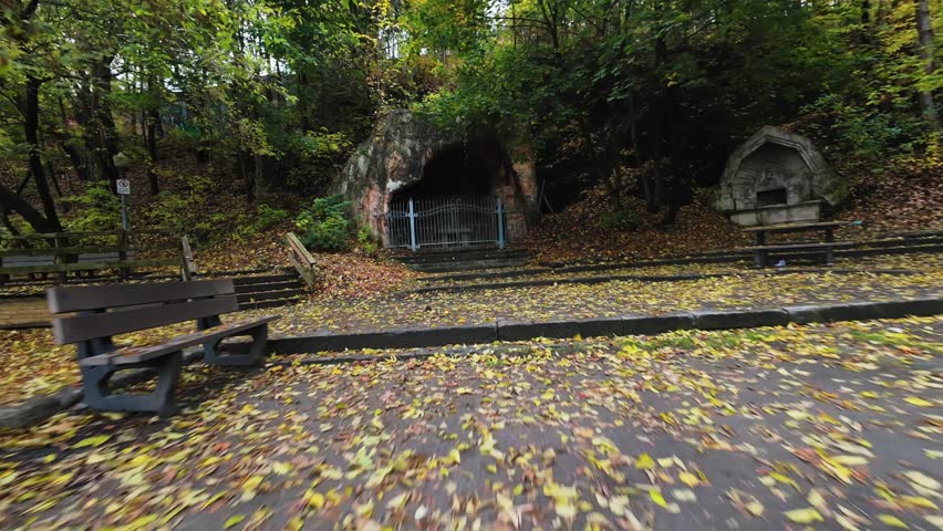 A smooth FPV drone flythrough along wooden stairs surrounded by golden autumn trees in a quiet forest park in Quebec, Canada. The cinematic movement captures the beauty of fall nature, colorful foliag